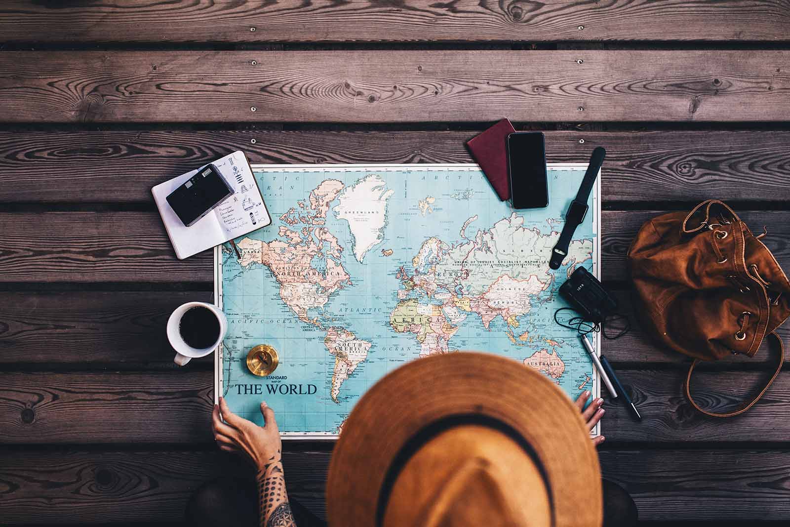 Girl planning travels with a world map | Top tips for travelling in a large group while keeping friendships intact