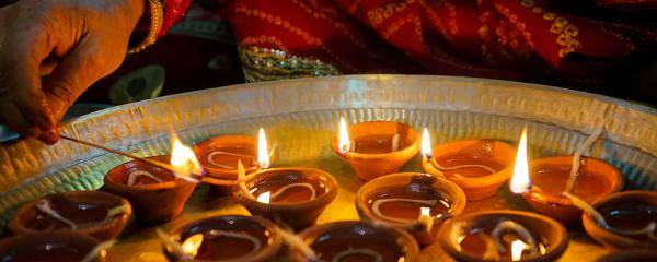 A hand lighting Diwali candles in small clay pots 