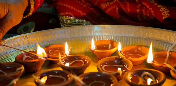 A hand lighting Diwali candles in small clay pots 